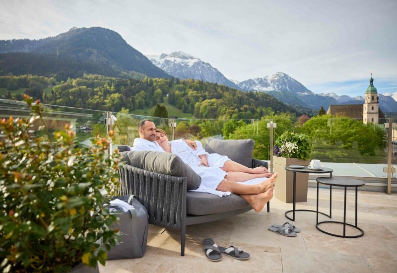 Pärchen in unseren Loungemöbeln auf der Dachterrasse mit traumhaftem Bergpanorama